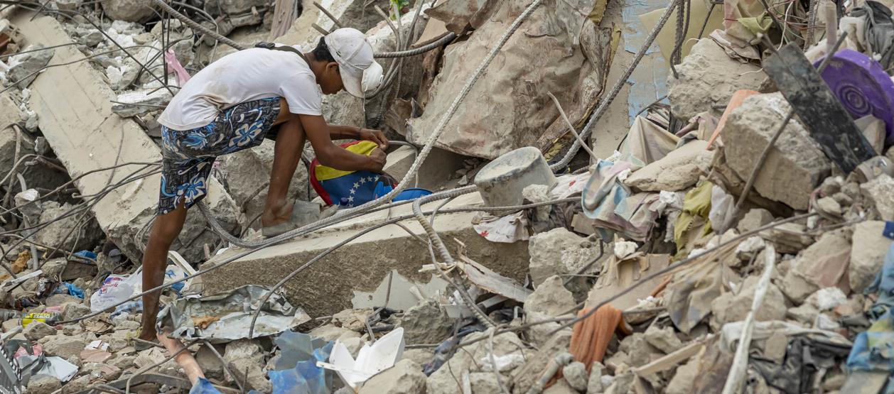 Una persona busca entre los escombros de edificios destruidos por terremotos.