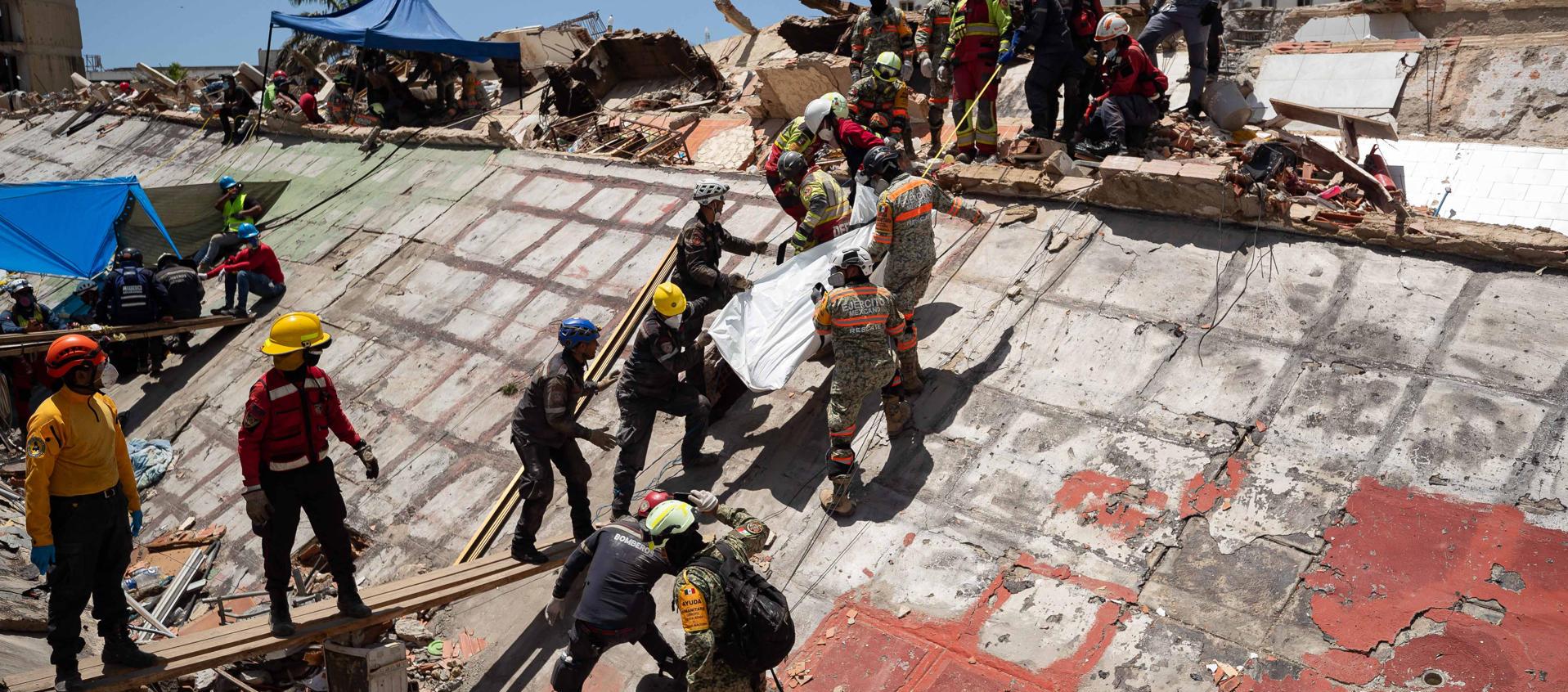 Rescatistas buscan cuerpos entre los escombros.
