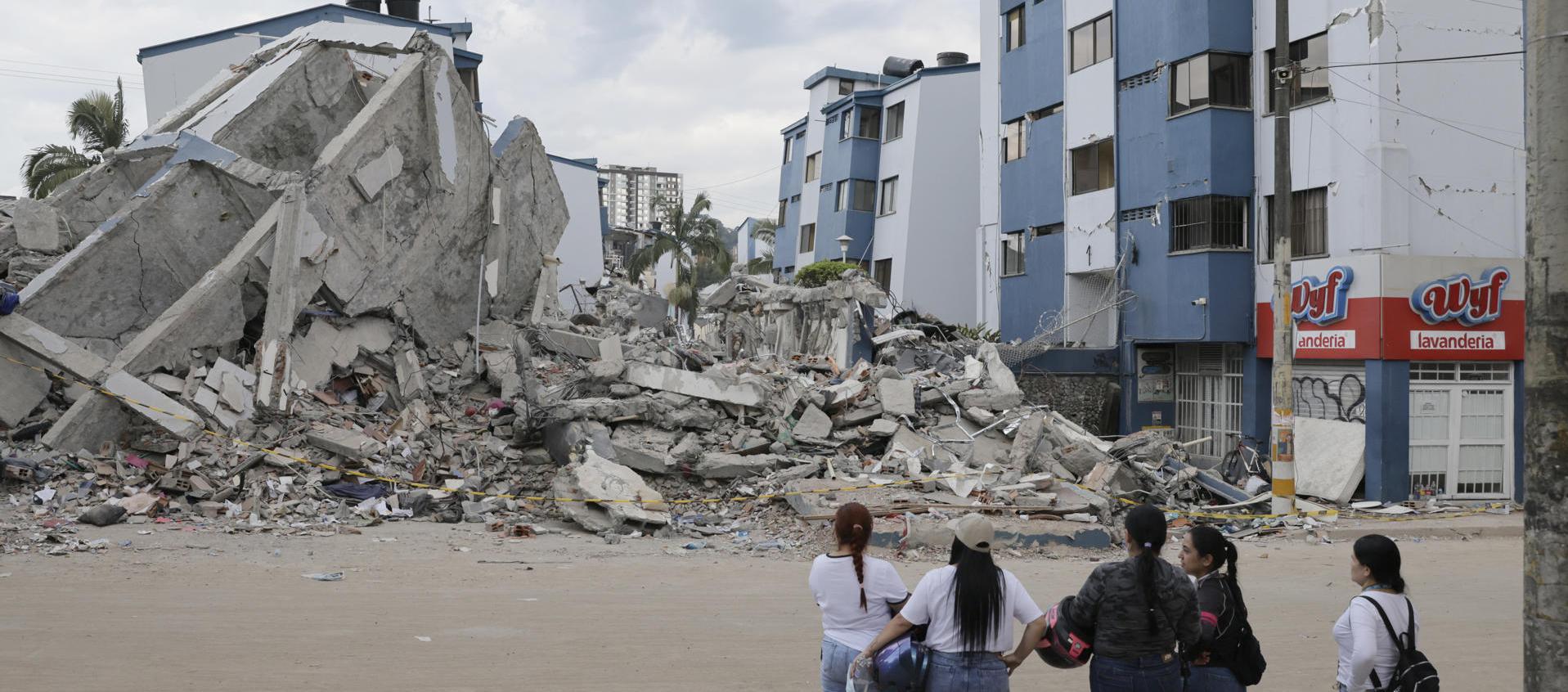 Personas observan los escombros de un edificio afectado por el terremoto en Pereira. 