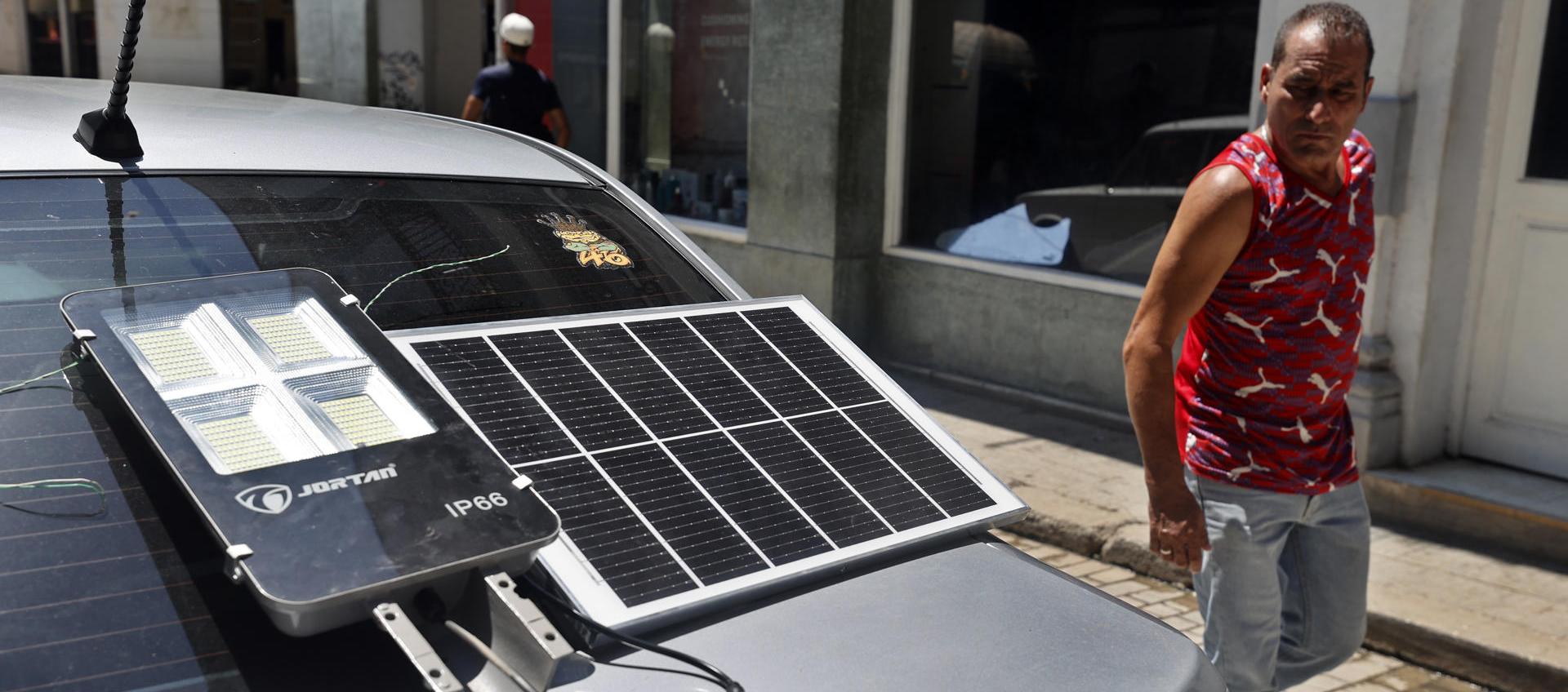 Hombre observa un panel solar que suministra energía a una lámpara.