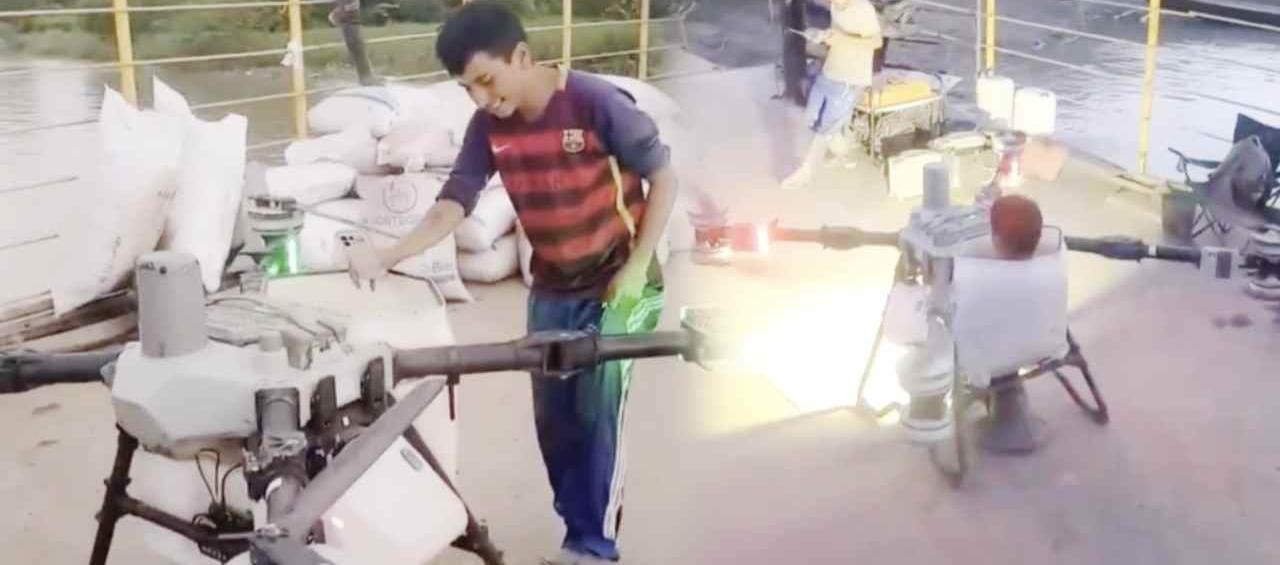 Joven sobre el dron aspersor.