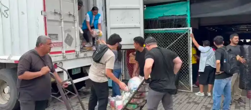 Miembros de la comunidad descargan una de las tractomulas con ayuda humanitaria. 