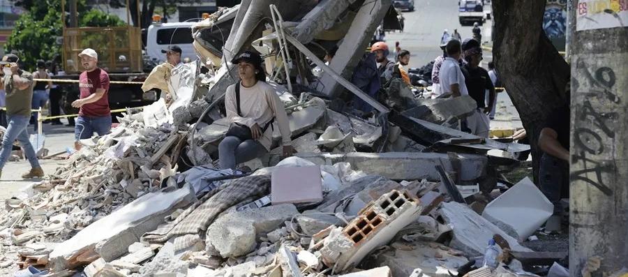 Una mujer espera entre los escombros de un edificio tras el terremoto de magnitud que sacudió a Pereira.