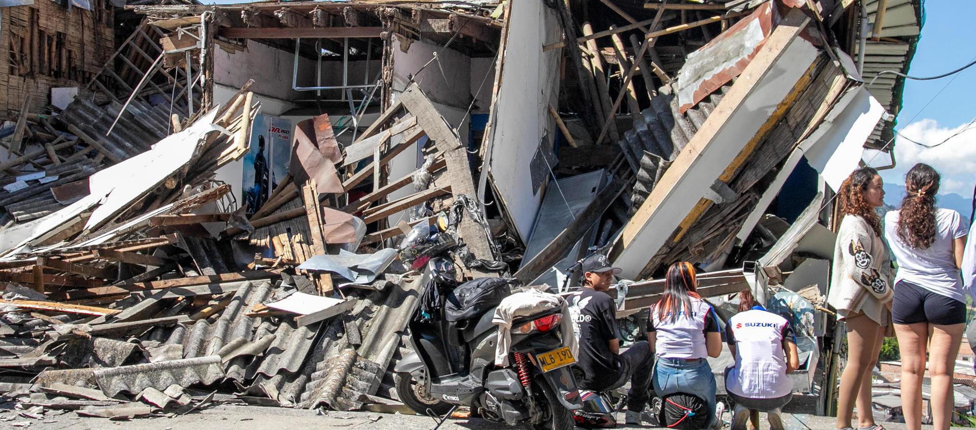 Personas observan una edificación destruida por un terremoto en Manizales