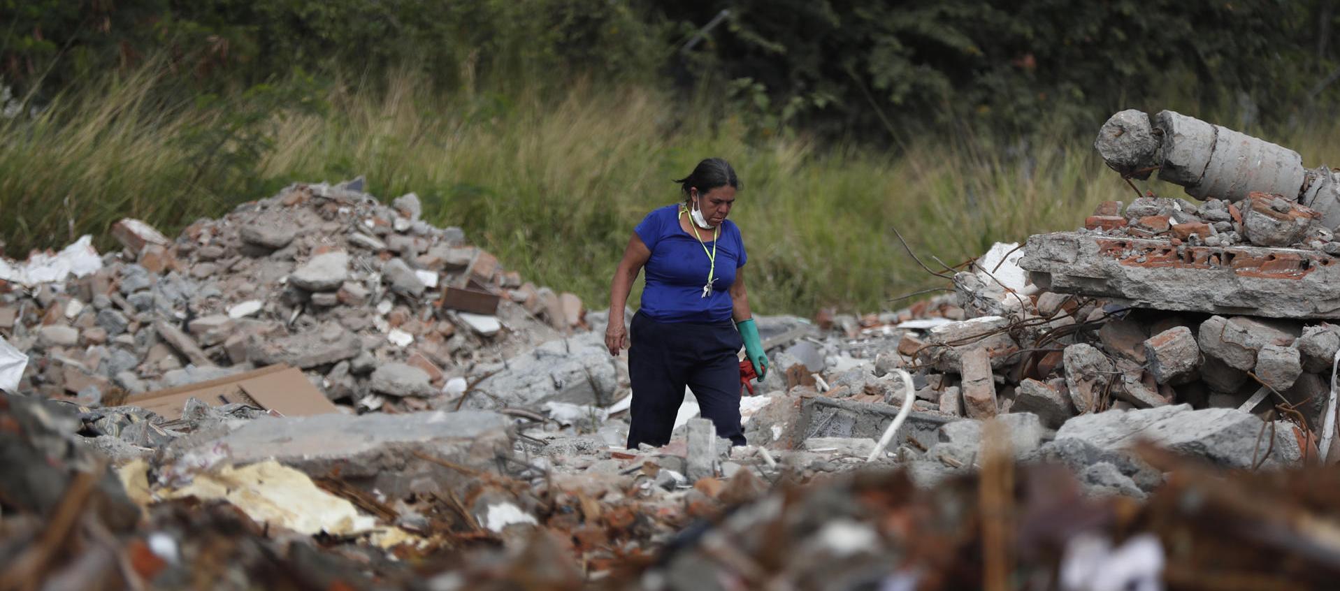 Una persona busca en los escombros de edificios colapsados.