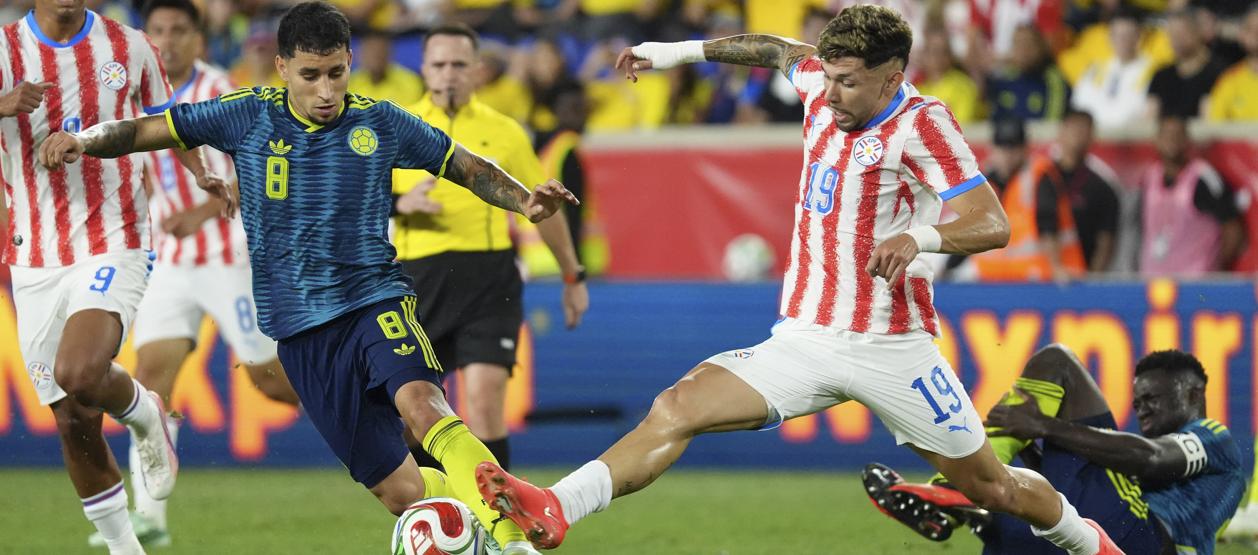 Gustavo Puerta disputa la pelota con el paraguayo Julio Enciso.