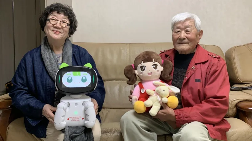 Lee Ha-seon y An Sang-ik sosteniendo el robot Dasomi y la muñeca Chorongi. 
