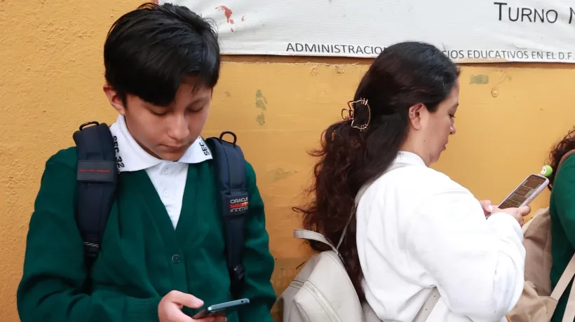 Un estudiante de secundaria usa el celular.