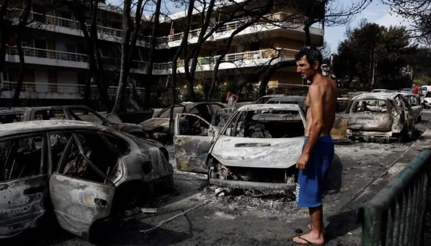 Un residente observa el estado en que han quedado varios coches calcinados tras el paso de las llamas por Mati, barrio del noreste de Atenas (Grecia) .
