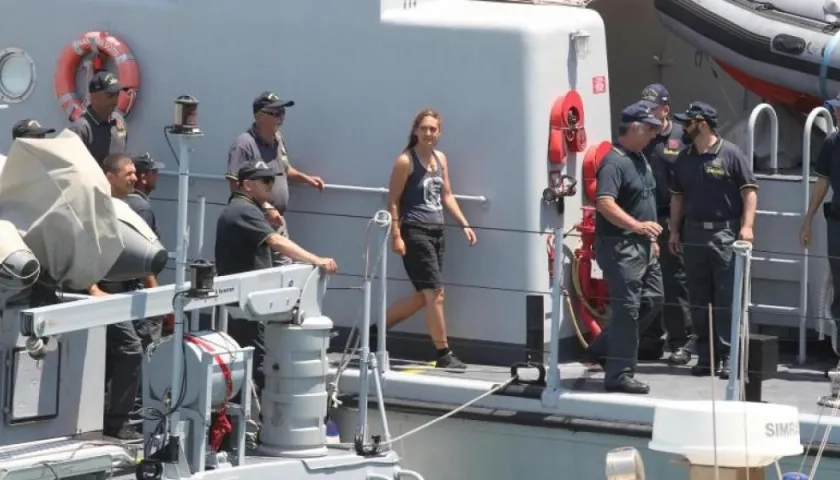 Carola Rackete (c), capitana del buque de rescate Sea Watch 3, es escoltada por efectivos de la Guardia di Finanza italiana a su llegada a Porto Empedocle (Italia) este lunes. 
