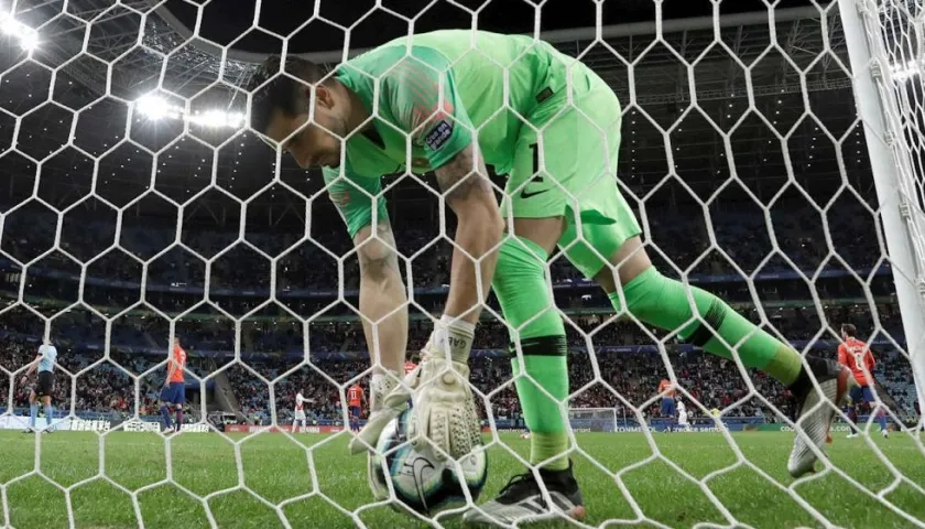 El arquero de Chile Gabriel Arias recoge el balón después de recibir un gol durante el partido Chile-Perú.