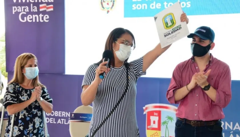 Una beneficiaria exhibiendo el título de vivienda,