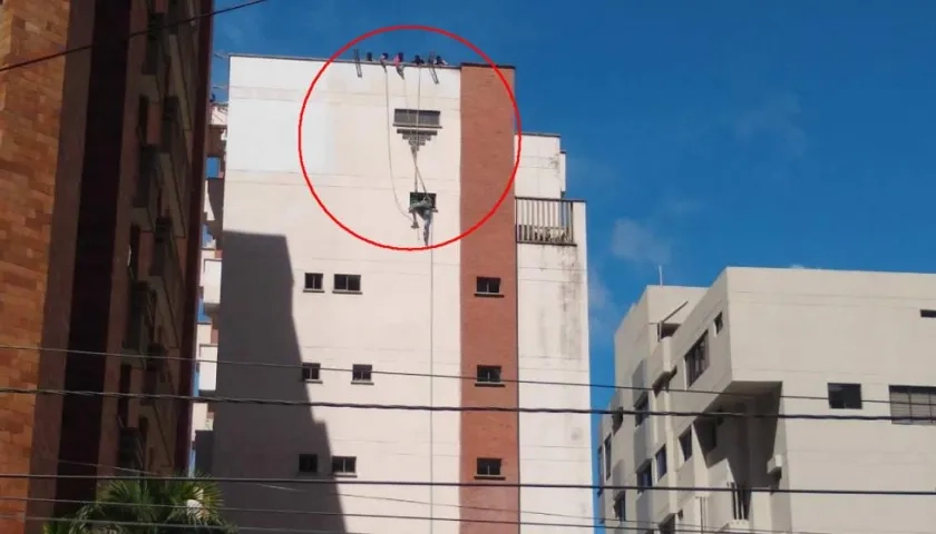 Los dos obreros colgando tras reventársele la guaya del andamio.