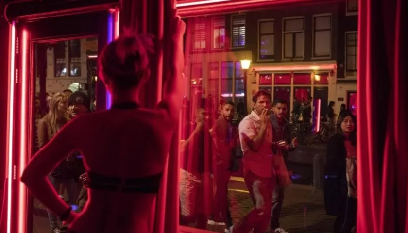 Jóvenes frente a uno de los escaparates del barrio Rojo de Amsterdam.