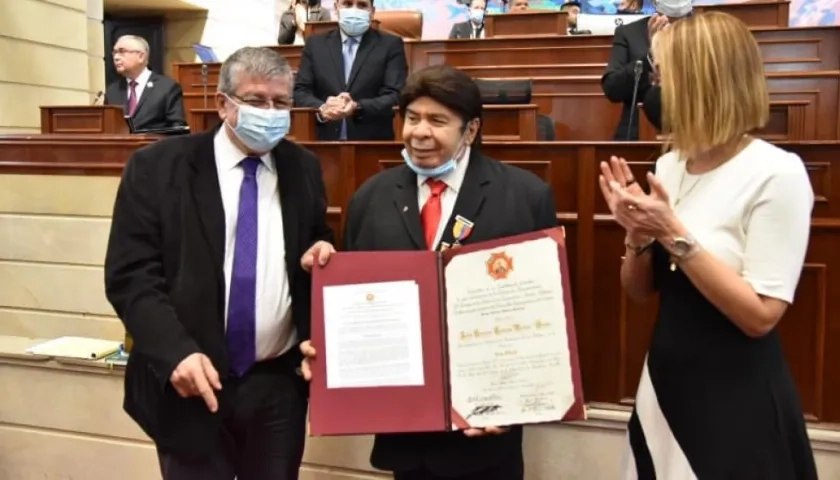 Julio Ernesto Estrada, recibiendo la condecoración por parte de los Representantes Jorge Gómez Vallejo y Jennifer Arias.