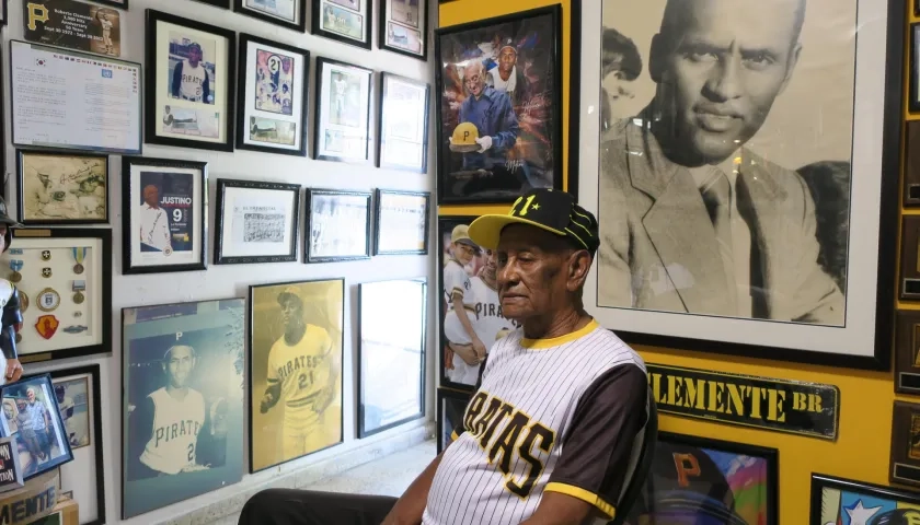 Justino, hermano de Roberto Clemente, rodeado de fotos del legendario beisbolista.