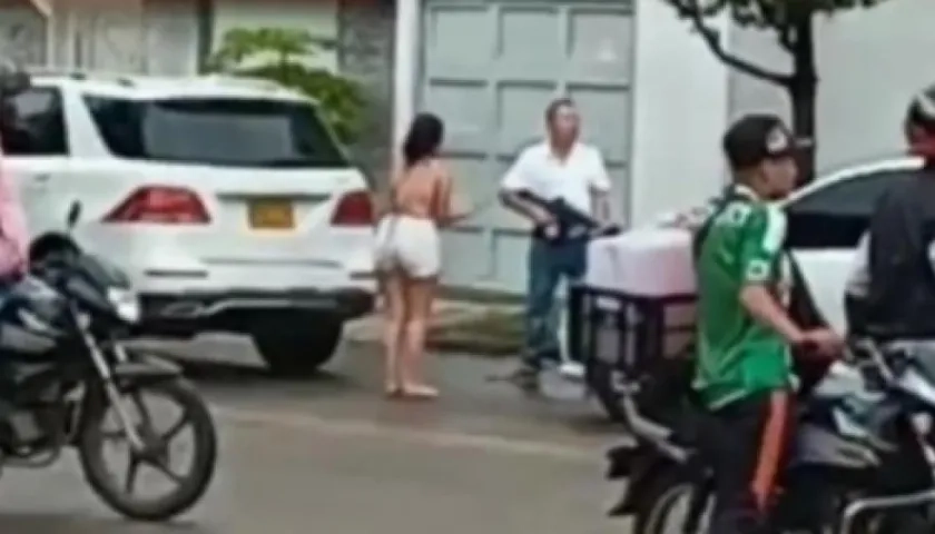 Julio César Yamin Berardinelli, con fusil en mano, discute con los ocupantes de un automóvil blanco.