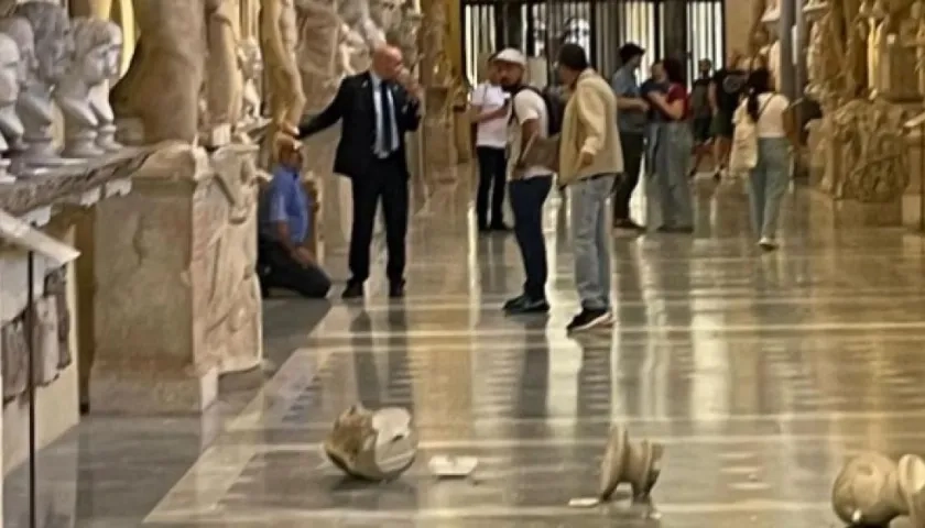 El sospechoso de derribar las esculturas aparece de rodillas rodeado de guardias de seguridad.