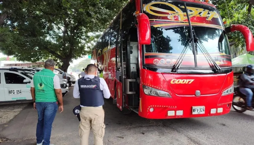 Funcionario de Migración Colombia inspeccionan un bus. 