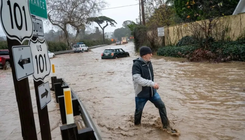 Un ciudadano camina entre una vía totalmente inundada en California.