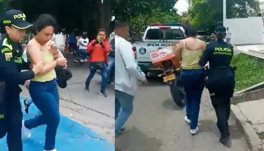 Policías conducen a una mujer luego de robo de un camión de valores cargado de dinero.