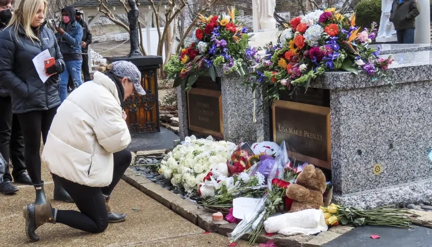 Una mujer se arrodilla ante la tumba de Lisa Marie Presley en Graceland, el hogar del cantante y actor estadounidense Elvis Presley.