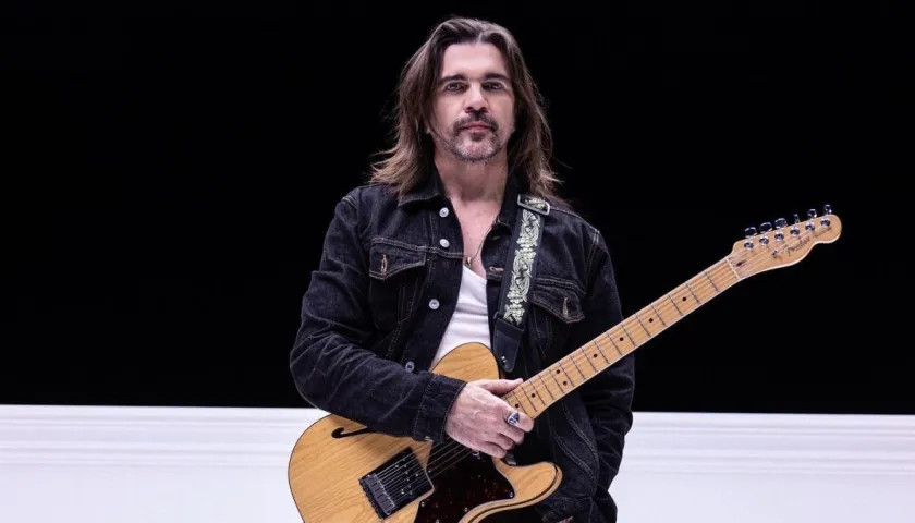 Juanes posando con una guitarra en medio de una presentación.