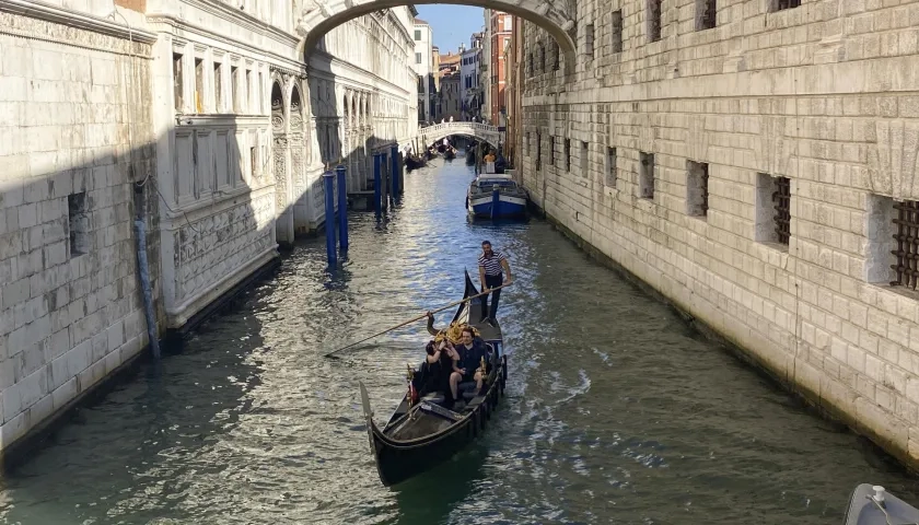 Una pareja disfruta de un viaje en góndola por un canal de Venecia.