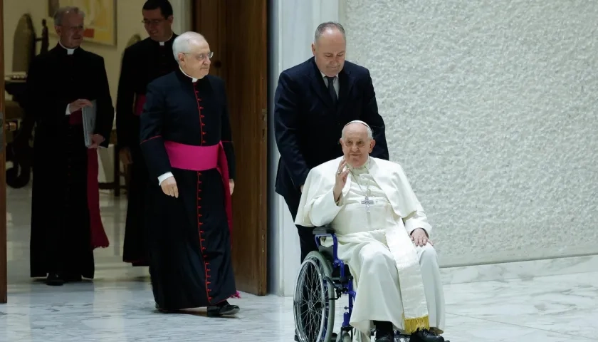 El papa Francisco saluda en silla de ruedas a su llegada al Aula Pablo VI.