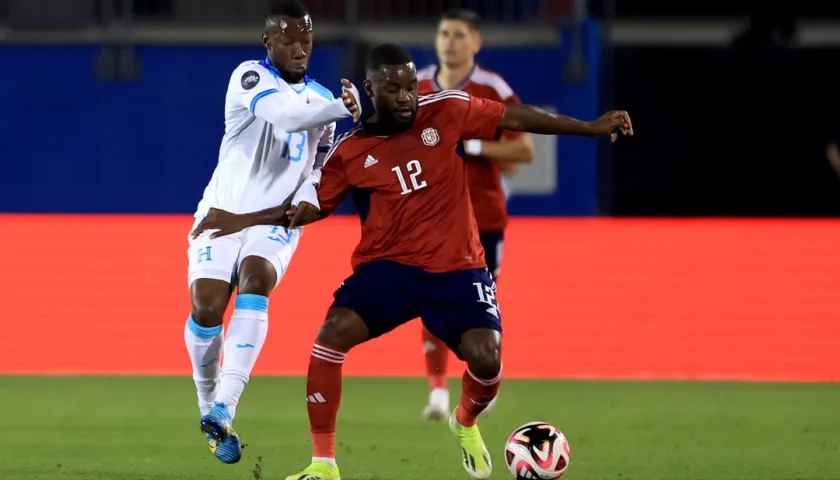 El costarricense Joel Campbell domina la pelota ante la marca de Darixon Vuelto, de Honduras. 