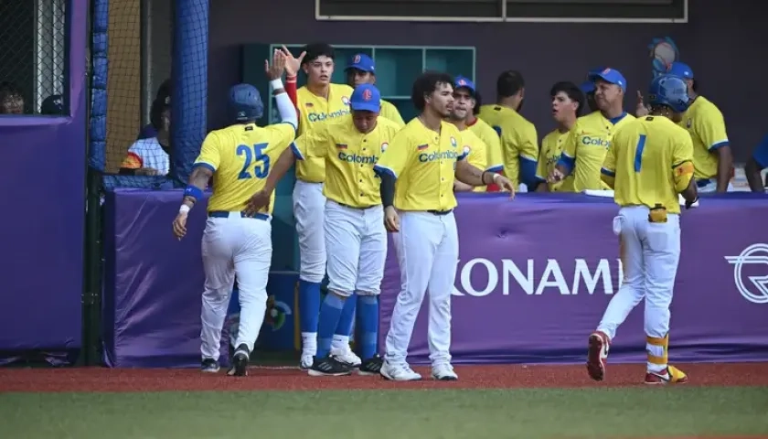 Peloteros de Colombia celebran una carrera en el dugout.