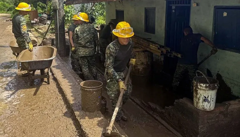 Soldados ayudan a remover escombros por un deslizamiento de tierra.