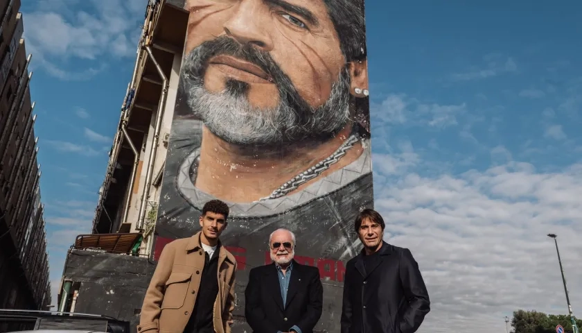 Giovanni Di Lorenzo, capitán del Nápoles, el presidente Aurelio De Laurentiis y el técnico Antonio Conte junto a un mural de Maradona.