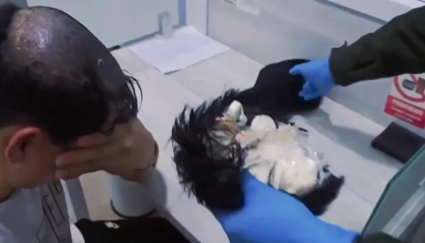 La peluca la llevaba puesta el hombre y allí le descubrieron la droga. 