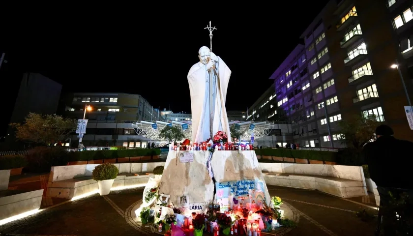 Flores y velas se encuentran a los pies de una estatua del Papa San Juan Pablo II fuera del Hospital Gemelli en Roma, Italia.