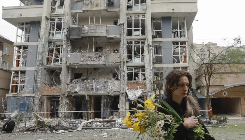 Mujer caminando junto a un edificio destruido tras el ataque nocturno. 