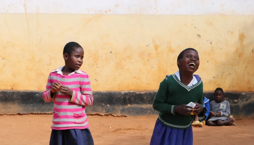 Dos estudiantes con discapacidad visual juegan y ríen durante el recreo.