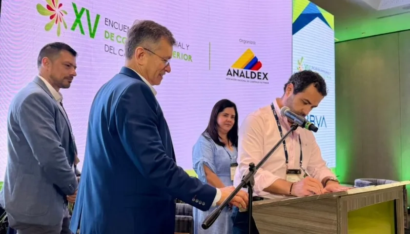 Hebert Mantilla, director de Comfamiliar Atlántico, firmando el convenio. A su lado, Javier Díaz, de Analdex.