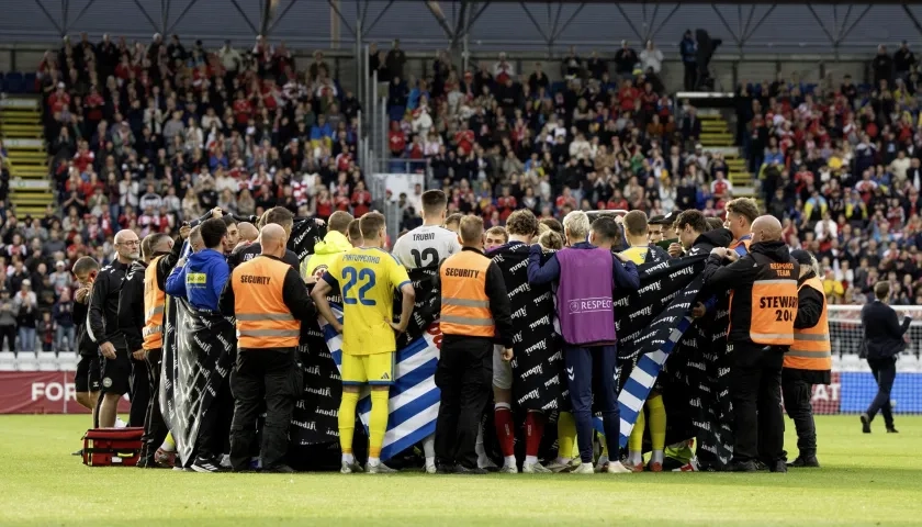 Jugadores de Dinamarca y Ucrania alrededor de Christian Eriksen después de que se desplomara.