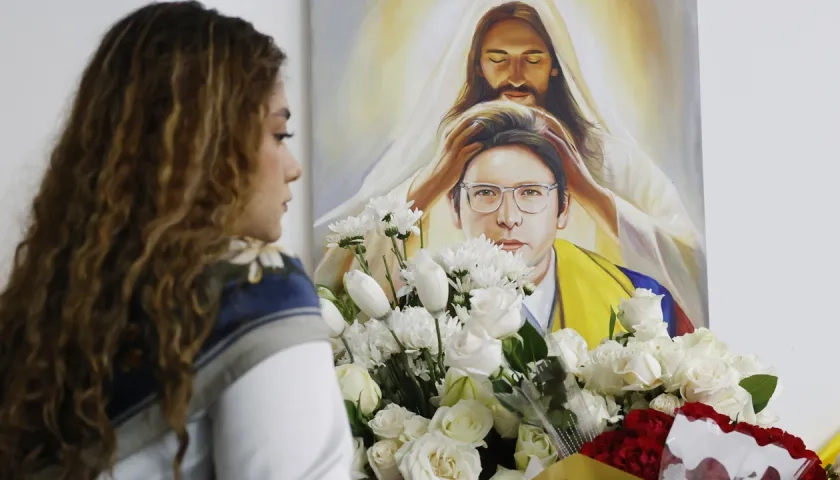 Una persona pone flores en un altar durante la conmemoración del primer aniversario del atentado contra Miguel Uribe Turbay en Bogotá.
