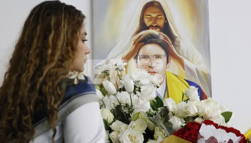 Una persona pone flores en un altar durante la conmemoración del primer aniversario del atentado contra Miguel Uribe Turbay en Bogotá.