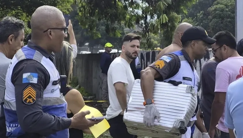 Policía transporta una maleta recuperada en el lugar donde ocurrió el accidente de dos helicóptero