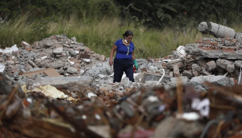 Una persona busca en los escombros de edificios colapsados.