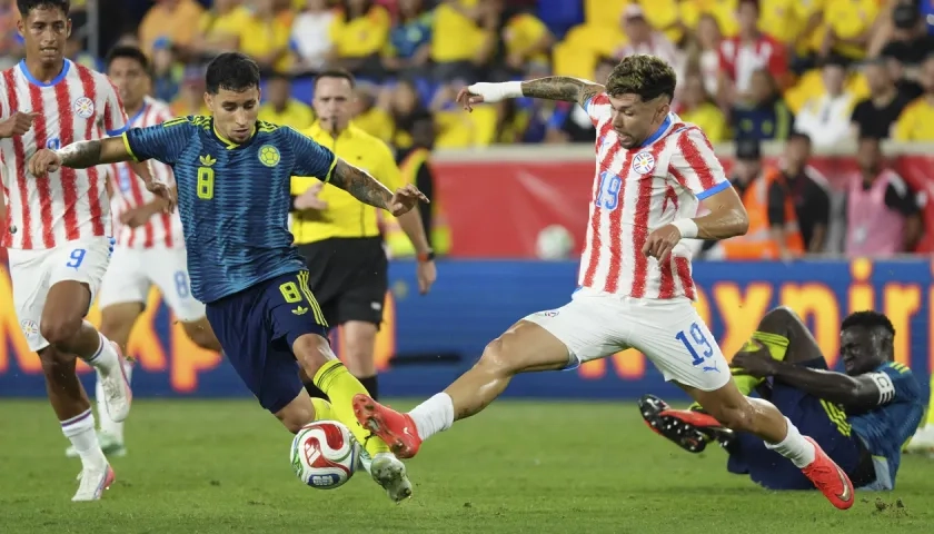 Gustavo Puerta disputa la pelota con el paraguayo Julio Enciso.