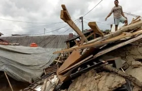 Un hombre subido en lo alto de su casa derrumbada en la localidad de Megamendung, en Bogor (Indonesia)
