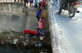 Momento en que vecinos ayudan a subir la moto donde se movilizaban padre e hijo.