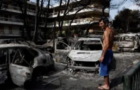 Un residente observa el estado en que han quedado varios coches calcinados tras el paso de las llamas por Mati, barrio del noreste de Atenas (Grecia) .
