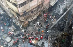 Varios bomberos inspeccionan los escombros tras el incendio declarado en la madrugada de este jueves en el barrio Chawkbazar del casco viejo de Dacca (Bangladesh).