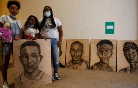 Familiares de Juan Manuel Montaño, asesinado en la masacre de Llano Verde, sostienen un retrato suyo durante un acto simbólico en homenaje a las víctimas, en Cali.