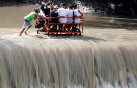 Varios lugareños cruzan en una carreta una presa desbordada en la frontera entre la provincia de Cavite y la ciudad de Las Piñas, en Filipinas, este domingo.